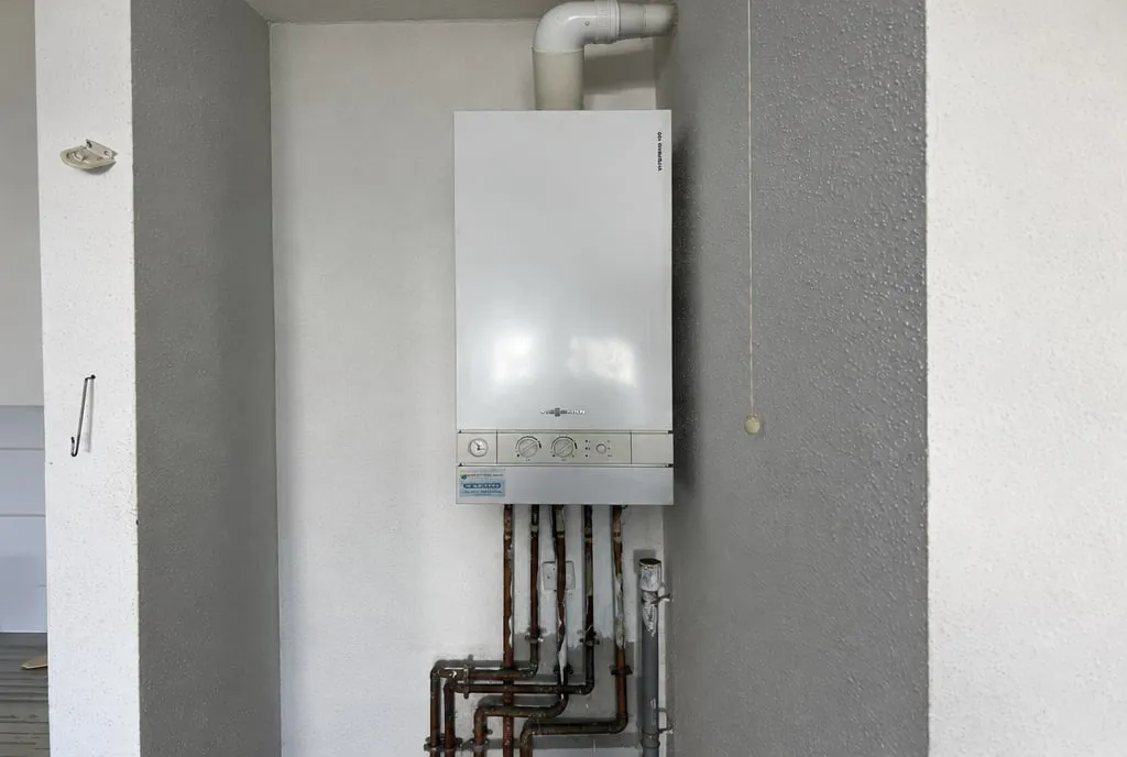 La même niche avant travaux : ancienne chaudière gaz murale Viessmann, tuyauterie oxydée